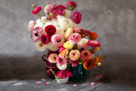 Ranunculus asiaticus or Persian buttercup bouquet in antique turquoise jug. Floral composition on grey backgoundの写真素材