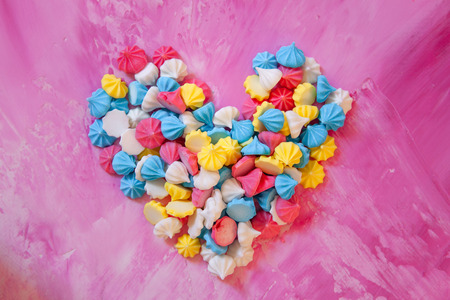 Pastel colored merengues cookies in heart shape on pink background top viewの写真素材
