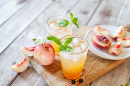 Peach cocktail with mint on white wooden background. Copy spaceの写真素材