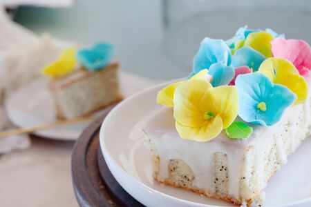 Close up of lemon and poppy seeds loaf cake decorated with pastel fondant flowers