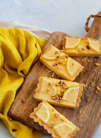 Top view of lemon tart on light bakkground, portions of summer dessert served on wooden trayの写真素材
