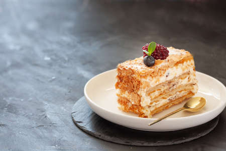 Traditional Millefeuille with vanilla cream patissier and berries on a white plate, cutted cake...