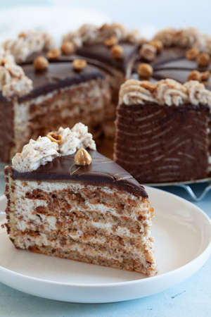Piece of delicious almond cake with daquoise and marzipan, decorated with hazelnut and whipped nut...