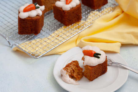 Vegan walnut carrot cake with cashew cream froasting, portions of pound cake on blue background
