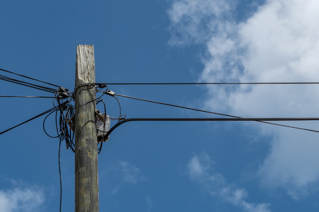 Wooden column with electric and communication cables and chain and cloudsの写真素材