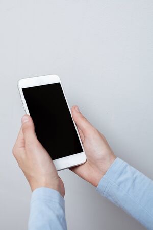 Closeup shot of a woman hold on mobile phone. Girl's hand holding a modern smartphone. Blank screen to put it on your own webpage or message.の写真素材