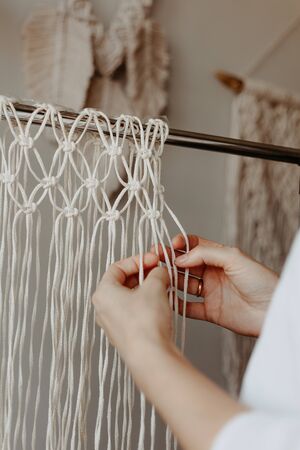 The girl weaves macrame. Boho decor in the process of weaving. Hand madeの写真素材