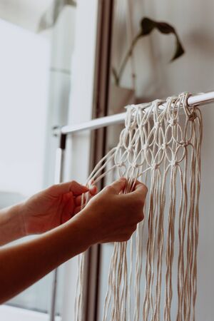 The girl weaves macrame. Boho decor in the process of weaving. Hand madeの写真素材