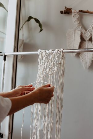 The girl weaves macrame. Boho decor in the process of weaving. Hand made