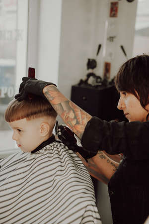 The work of the barbershop. Haircut of a boy in a barbershop. Children's haircutの写真素材