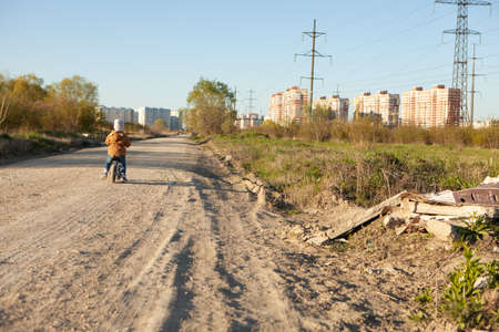 A boy rides a balance bike in a clearing. Spring mood. Sunの写真素材