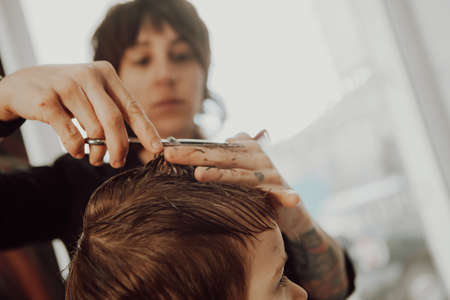 The work of the barbershop. Haircut of a boy in a barbershop. Children's haircutの写真素材