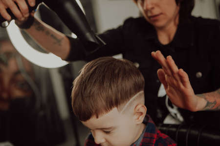 The work of the barbershop. Haircut of a boy in a barbershop. Children's haircutの写真素材