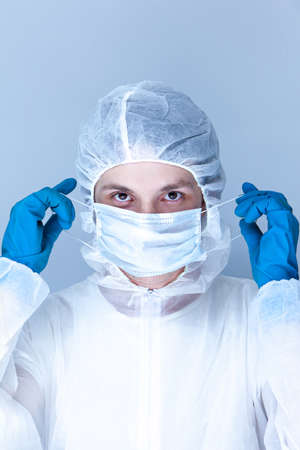 a man in a protective suit, gloves and puts a mask on his face. The concept of health care.の写真素材