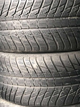A lot of old used tires are lying on top of each other. Replacing winter and summer tires. Seasonal tire replacement conceptの写真素材
