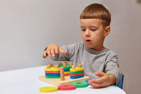 The boy is playing in his room. Learning shapes and colors. A child plays with a sorter. Educational logic toys for kid's. Montessori Games for Child Development.の写真素材