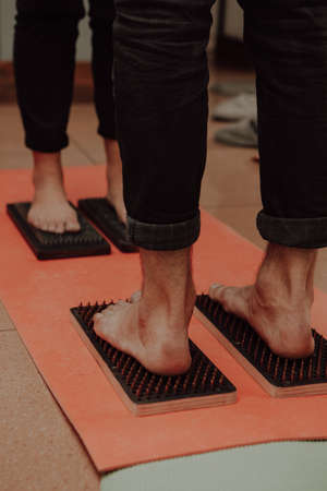 Group practice of standing on nails. Closeup of yoga person standing on sadhu board with sharp...