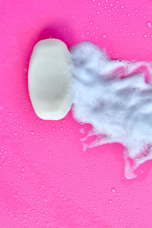 Washing concept. Foam bubbles and brick of soap on pink background. Cleaning serviceの写真素材