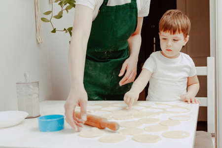 Happy family in the kitchen. Dad and son preparing the dough, bake cookies. Casual lifestyle in home interior, pretty child, holiday concept, rolling pin, coockie cutters and dough.の写真素材
