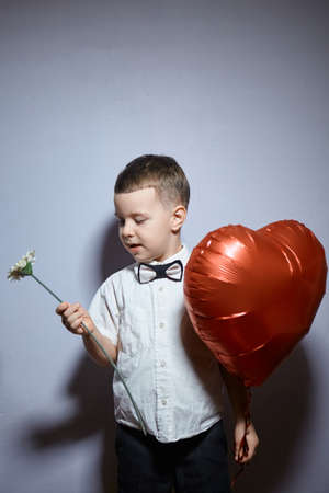 Valentine's day. Happy boy stands and holds red ball hearts on a white background.の写真素材