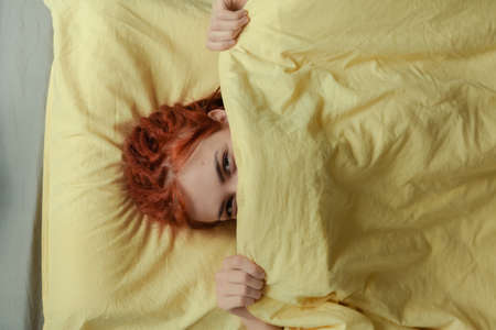 Very pretty redhead girl with dreads on bed in bedroom in the morning. A feminine, gentle girl. Healthcare and Sleep Concept.の写真素材