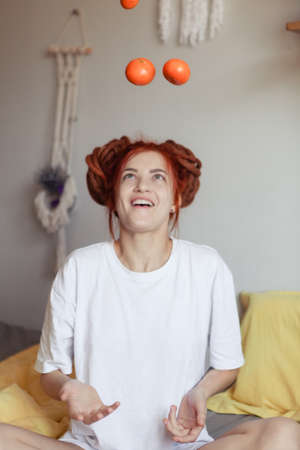 Very pretty redhead girl with dreads on bed in bedroom in the morning. A woman juggling with...