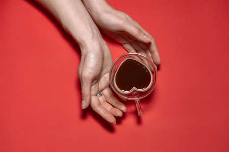 Valentines day hearts background. Woman Holding Hot Cup Of Coffee, With Heart Shape Stock Photo. Beautiful decorative heart shaped on red background, valentines day conceptの写真素材