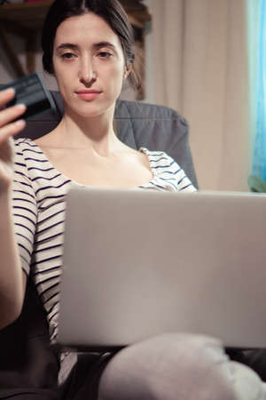 Young confident pretty woman working with laptop and transferring money with online banking using...