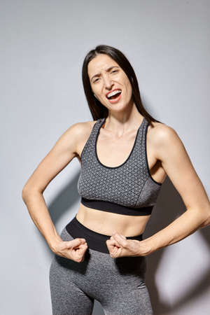 A woman in sportswear shows off her muscles and laughsの写真素材