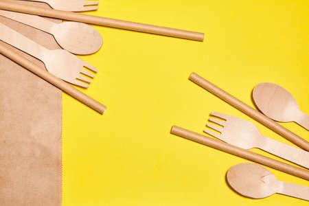 Eco-friendly disposable tableware made of bamboo wood and paper. Disposable tableware from natural materials, wooden spoon, fork, eco-friendly. Place for text. Layout of wooden disposable teaspoonsの写真素材