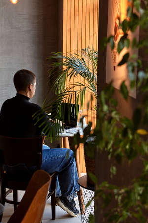A young girl with short hair and a nose piercing is sitting in a cafe and working on a laptop. The concept of freelancing and remote work or training.の写真素材