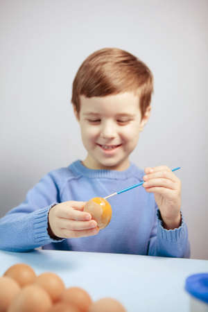 Little Boy painting Easter Eggs with Paint at Home. Children's Easter creativity. A child decorate Easter eggs.の写真素材