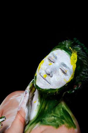 Portrait of a woman with a painted face. Creative makeup and bright style.Girl with colored face painted. Art beauty image.girl with colorful paint on her face.の写真素材