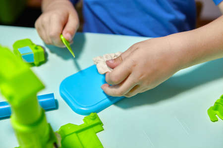 Child is sculpting with modeling clay. Art activity for children, indoor fun for kids concept. Close up and selective focus face and hands boy. Fun time for children activity at home or school.の写真素材