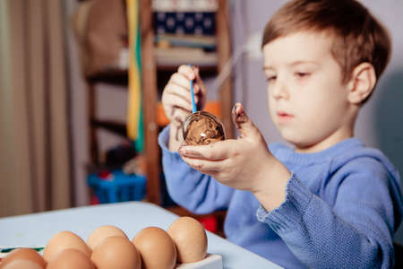 Little Boy painting Easter Eggs with Paint at Home. Children's Easter creativity. A child decorate Easter eggs.の写真素材