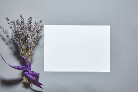 Lavender blossom with white paper sheet mockup on gray background. White paper empty blank, dried flowers on gray table. Invitation card mockup.Flat lay, top view, copy space, mockupの写真素材