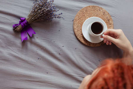 Very pretty redhead girl with dreads on bed in bedroom in the morning. A feminine, gentle girl. Coffee morning concept.の写真素材