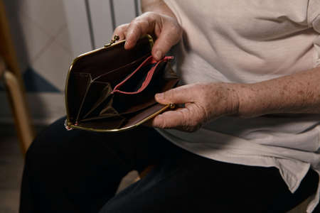 The older woman counts the money. An elderly woman Caucasian old woman gray-haired grandmother takes money out of her purse and counts it. Old hands hold bills.の写真素材