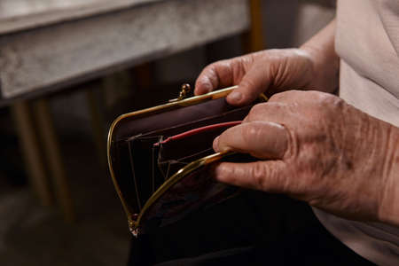 The older woman counts the money. An elderly woman Caucasian old woman gray-haired grandmother takes money out of her purse and counts it. Old hands hold bills.の写真素材