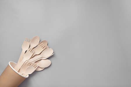 Wooden spoon, fork, paper cups gray background. Disposable tableware made of natural materials. The concept of a zero waste, sustainable lifestyle. Eco-friendly disposable tablewareの写真素材