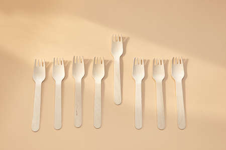 Wooden spoon, fork, paper cups on beige background. Disposable tableware made of natural materials. The concept of zero waste, sustainable lifestyle. Eco-friendly disposable tablewareの写真素材