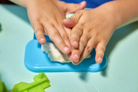 Child is sculpting with modeling clay. Art activity for children, indoor fun for kids concept. Close up and selective focus face and hands boy. Fun time for children activity at home or school.の写真素材