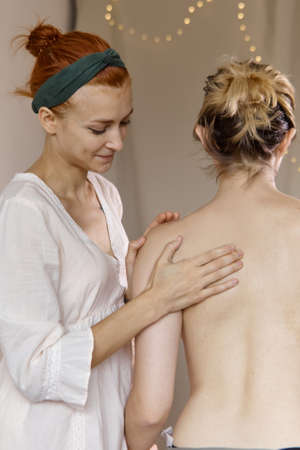 Chiropractor helping female patient with scoliosis, low back pain or other spine problems. A female...