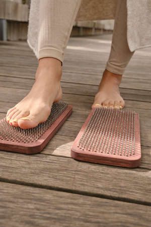 The practice of self-knowledge in the park. A woman with a pedicure stands on sharp nails. Female legs and Sadhu board close-up. Yoga. Meditation.の写真素材