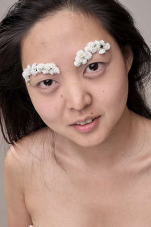 Attractive young Asian woman with flowers. Stunning brunette girl with flowers on the face. Close up...