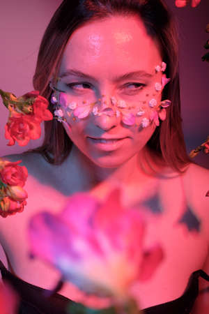 Beautiful woman with flowers on her face, conceptual photo. The idea of femininity and springの写真素材