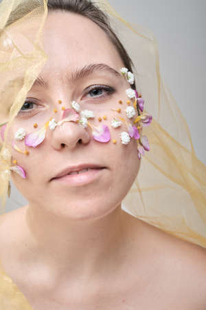 Beautiful woman with flowers on her face, conceptual photo. The idea of femininity and springの写真素材