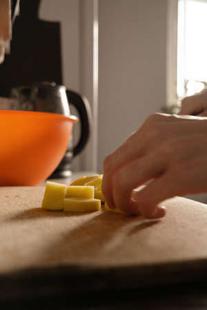Cooking. Close-up of a kitchen knife in female hands. A woman cuts vegetables for soup. A knife cuts potatoes on a wooden boardの写真素材