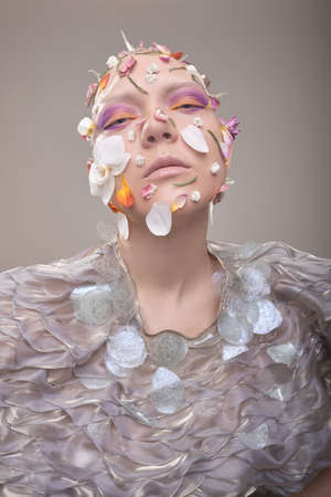 A beautiful woman without hair with flowers on her head, a conceptual photo with an unusual model