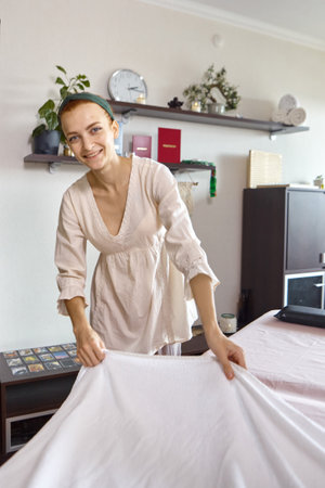 A female massage therapist prepares her workplace for receiving clientsの写真素材